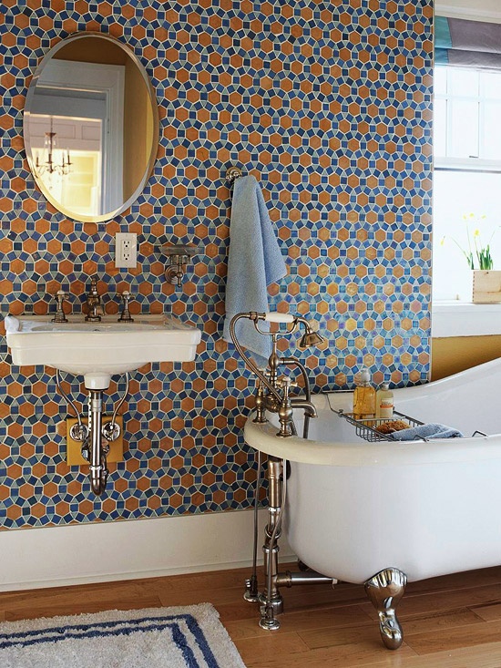 a vintage bathroom with a blue and mustard tile accent wall, with a clawfoot bathtub and a mirror plus a wall-mounted sink is all cool