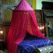a bright Moroccan bedroom in blue and pink, with lots of patterns and an ornate mirror