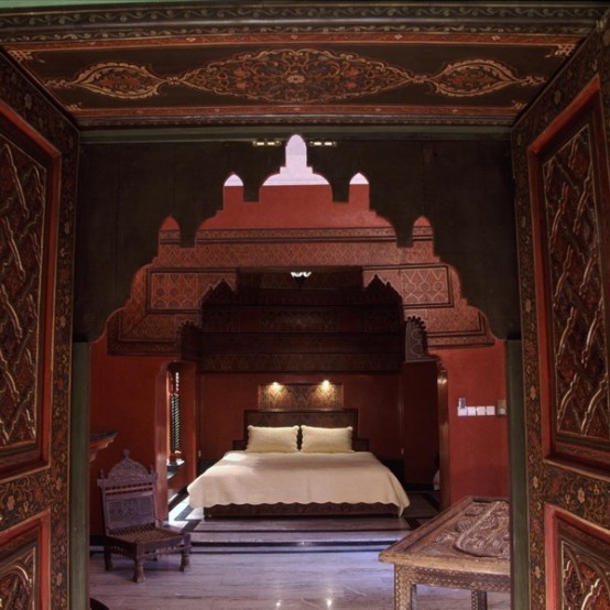 a small Moroccan bedroom in a beautiful alcove done in burgundy and gold, with lights and natural light from the window