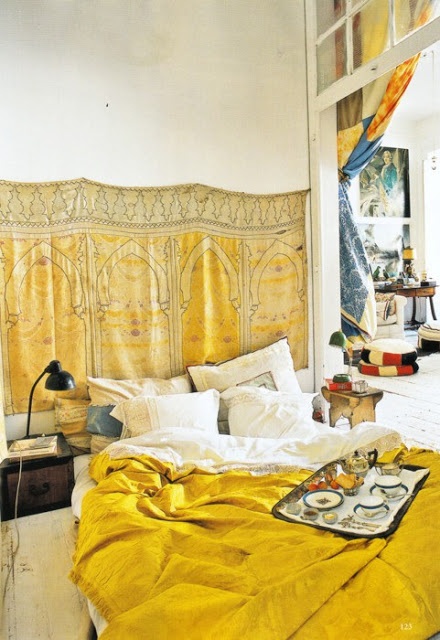 a small mustard-sprinkled bedroom with a blanket on the wall and matching bedding plus vintage nightstands
