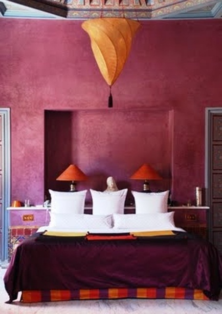 a burgundy and fuchsia Moroccan bedroom with touches of orange and a Moroccan lantern