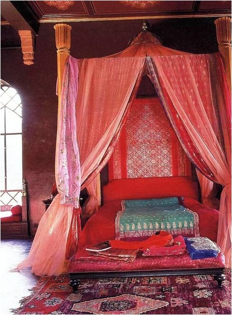a red Moroccan bedroom with plenty of pattern, boho rugs and bedding and carved wooden furniture