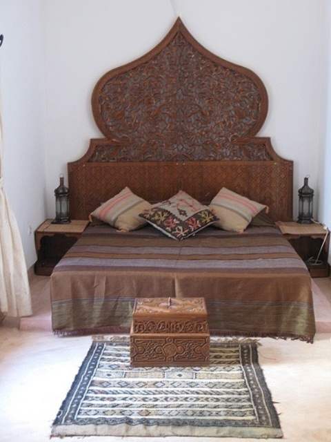 a statement carved owoden bed, nightstands and a chest plus catchy textiles create a chic Moroccan space