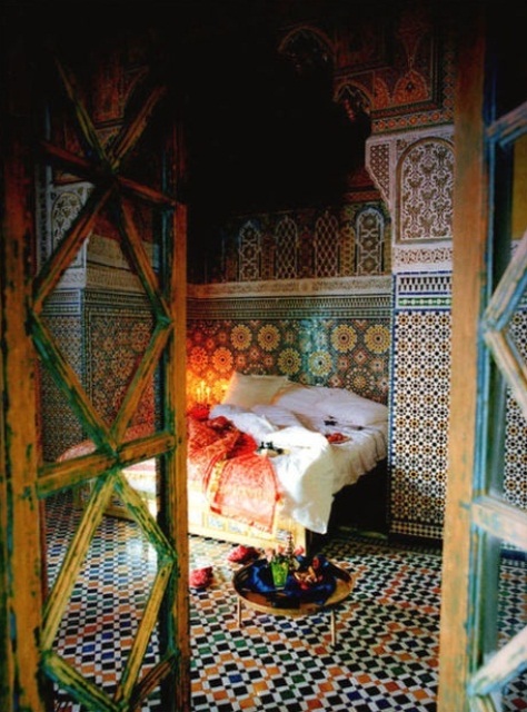 a colorful bedroom fully clad with bright mosaic tiles, a low table and lots of candles feels totally Moroccan-like