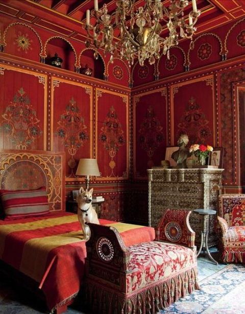 a red and marigold bedroom with carved wooden furniture and a crystal chandelier screams Moroccan