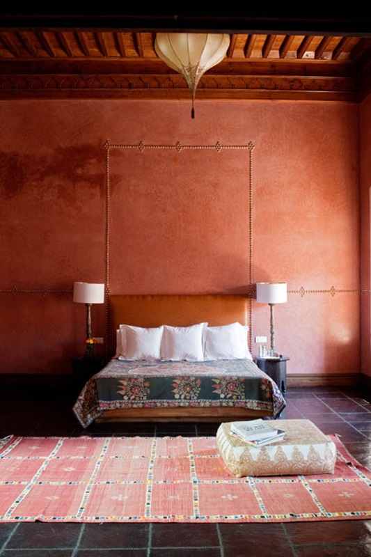 a rust-colored and red Moroccan living room with a leather bed, a boho rug and a lantern