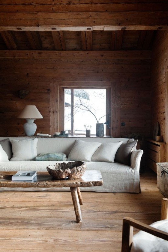 a modern to contemporary chalet living room clad with wood, with a neutral sofa, a wooden coffee table and some chairs