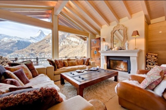a neutral chalet living room with a view, a fireplace, neutral seating furniture, a coffee table and some colorful pillows