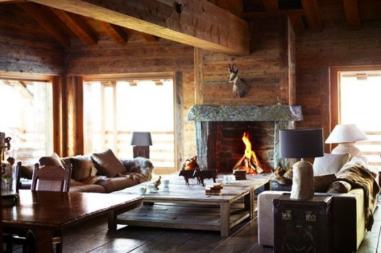 a cozy modern chalet living room with a fireplace, leather sofas, a low coffee table, wooden beams and lots of aged and reclaimed wood in decor