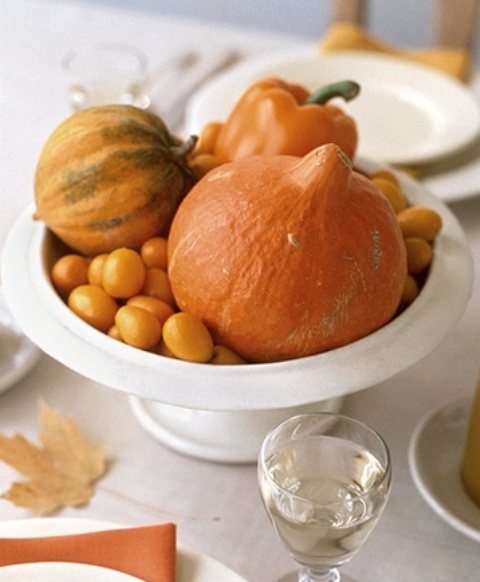 a natural Thanksgiving centerpiece of a white bowl filled with gourds and pumpkins and some smaller fruit is bold and very natural