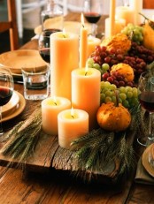 a natural Thanksgiving tablescape with an uncovered table, neutral porcelain, a wooden bowl with candles, greenery and frapes