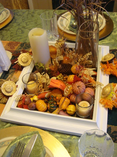 a natural Thanksgiving centerpiece of a frame, faux pumpkins, gourds, berries, nuts and blooms is a pretty fall decor idea