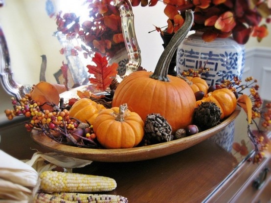 a wooden bowl with berries, pumpkins, pinecones and vine balls is a lovely Thanksgiving centerpiece to rock