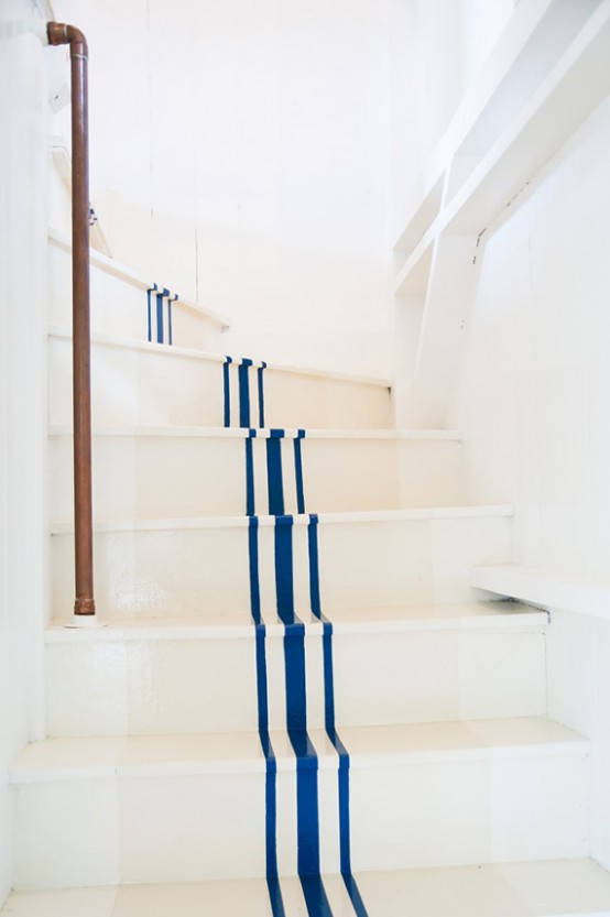 a nautical staircase with navy stripes and a copper pipe instead of railing is a very cool and very fresh