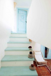a nautical staircase with light blue steps and pebbles right on them and a light blue door