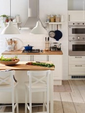 a Scandinavian kitchen with white cabinets, butcherblock countertops, a kitchen island with tall stools and stainless steel appliances