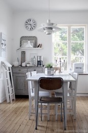 a neutral Scandinavian kitchen with white and grey shabby chic cabinets, a dining zone accented with a pendant lamp and some decor
