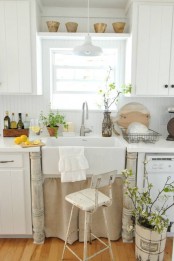 a white cottage kitchen with planked cabinets, a vintage sink with a stand, pots and greenery