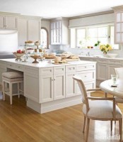 a tan cottage kitchen with shaker and glass cabinets, a large kitchen island, elegant chairs and a dining zone