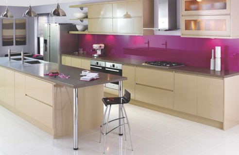 a bold kitchen done in tan, with stainless steel appliances and surfaces plus a fuchsia backsplash that wows