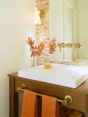 bright orange, red and white mini tiles to accent the sink and orange towels to make the space brighter