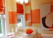 orange stripes on the walls, an orange shade, artworks and a floral arrangement for bright touches in the neutral space