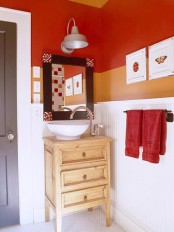 orange and rust colored walls make this bathroom bright, fun and bold, white tiles and a wooden vanity calm down the space