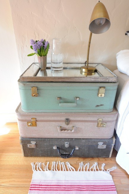 a stack of vintage suitcases   a black, a blush and an aqua one, with a mirror top and a chic brass table lamp