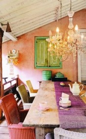 a bright boho dining room with a vintage chandelier, a rustic wooden table, colorful wicker chairs and touches of mint