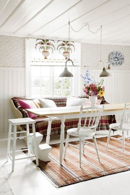 a neutral dining room with white furniture and bright boho textiles and pendant lamps