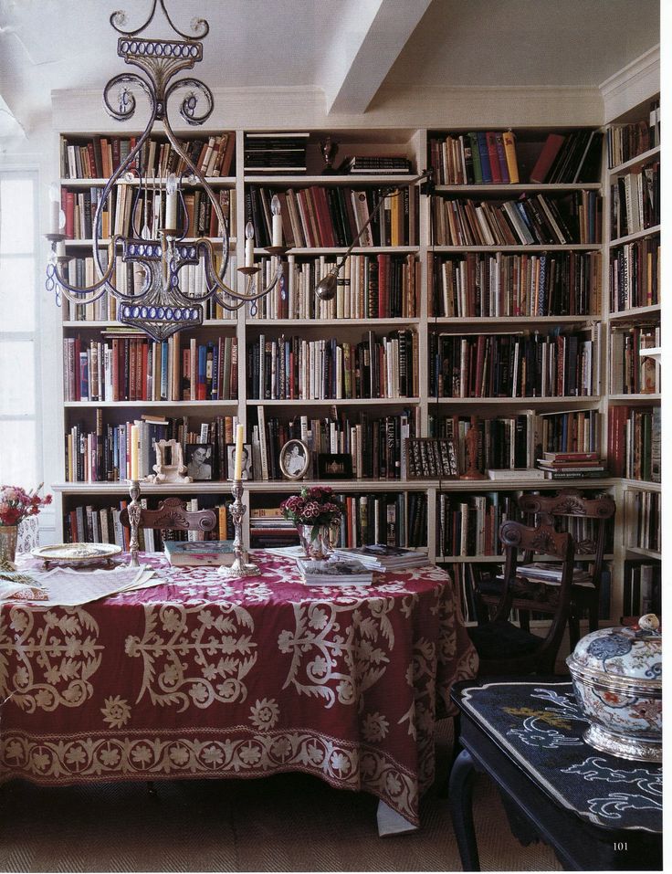 a vintage dining space with bookshelves, vintage carved wooden chairs and a table plus boho textiles