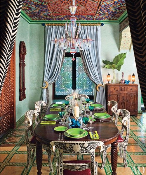 a brigth Eastern dining room with a carved stained wooden table, painted chairs, carved wooden furniture and an ornate ceiling