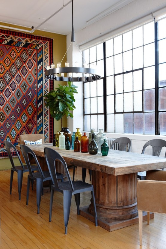 an eclectic dining room with a wooden table, metal and leather chairs, a boho rug on the wall