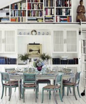a vintage dining room with blue chairs, a grey vintage table, artworks and books for an elegant touch