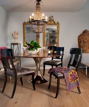 a modern dining room with chic furniture, a refined chandelier, an oversized mirror in a gold frame and an Asian statue head