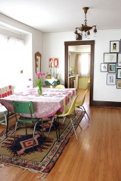 a colorful boho dining space with a hairpin leg table, mismatching chairs, a vintage chandelier and bright boho textiles