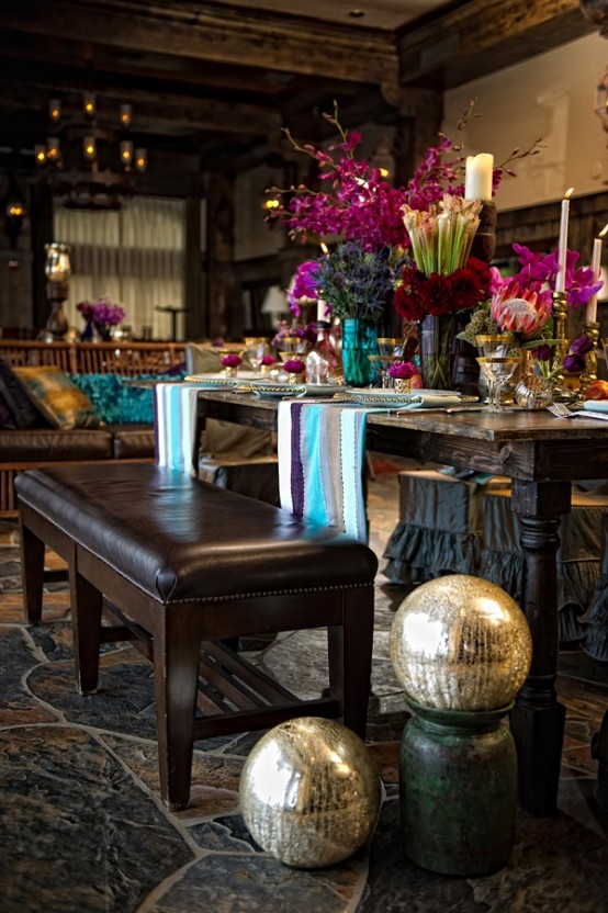 a moody Moroccan dining space with dark furniture, bright blooms, metallics and colorful boho textiles