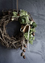 a wild twig and stick fall wreath with greenery, acorns, pinecones and nuts and a bow is a very woodland-inspired piece