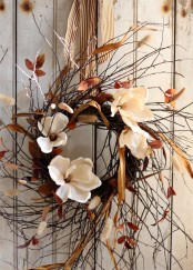 a chic twig fall wreath with white blooms, dried leaves, amber ribbons and a striped ribbon is a cool dried fall decoration