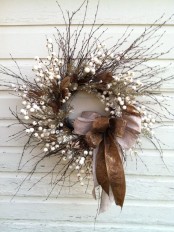 a textural twig wreath with faux berries, brown leaves, two large bows and silver branches for fall to winter period