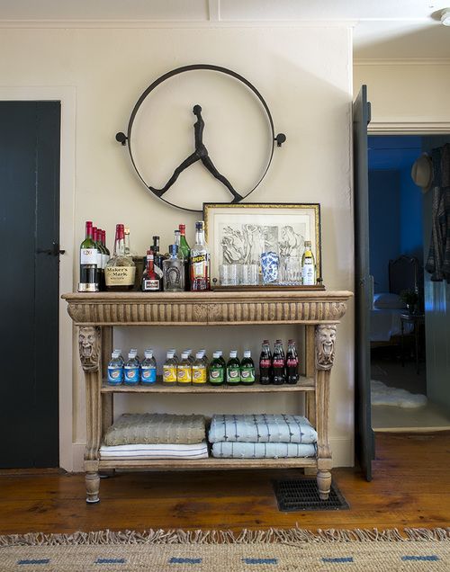 a refined vintage home bar made of a vintage inlay table, an artwork and a unique clock is a cool solution for a vintage space