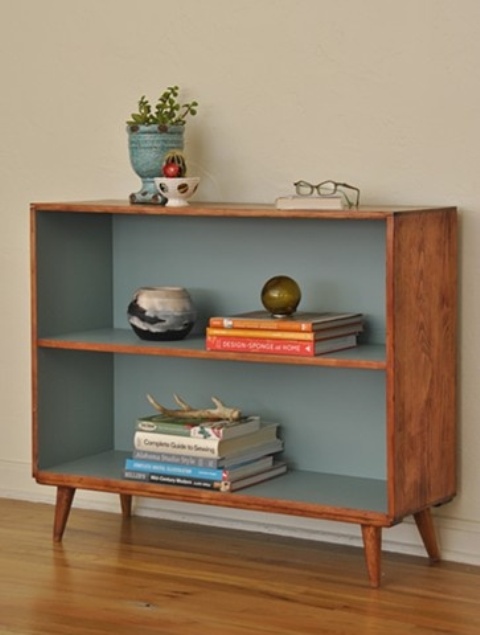 a box shaped mid-century modern bookcase with muted blue lining looks chic and adds a sutble touch of color
