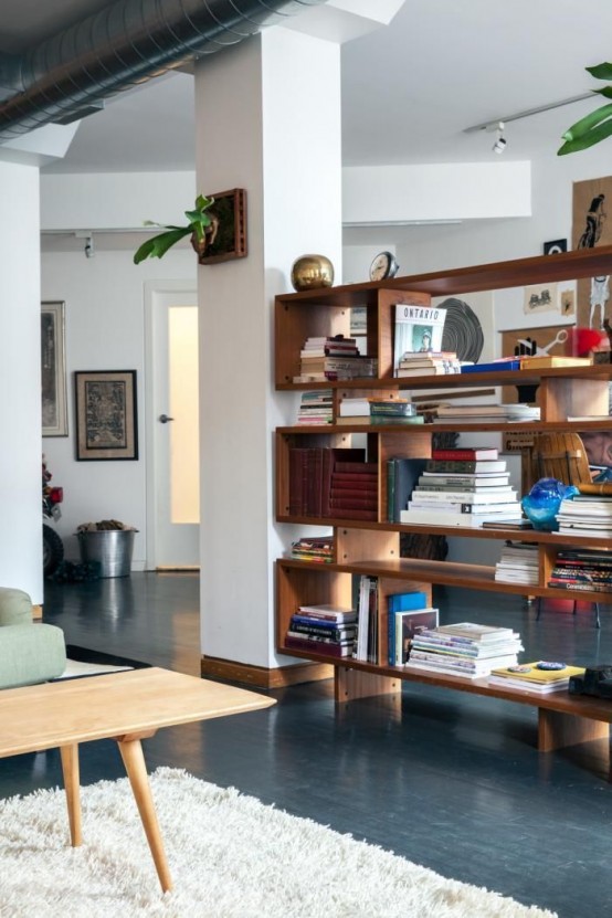 a rich-stained wood bookcase made of long boxes doubles as a space divider without looking bulky