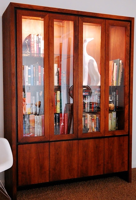 a large redwood bookcase with glass doors and soem storage space plsu glass shelves inside