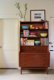 a brown wood mid-century modern bookcase with open shelves and some drawers can be also used as a desk