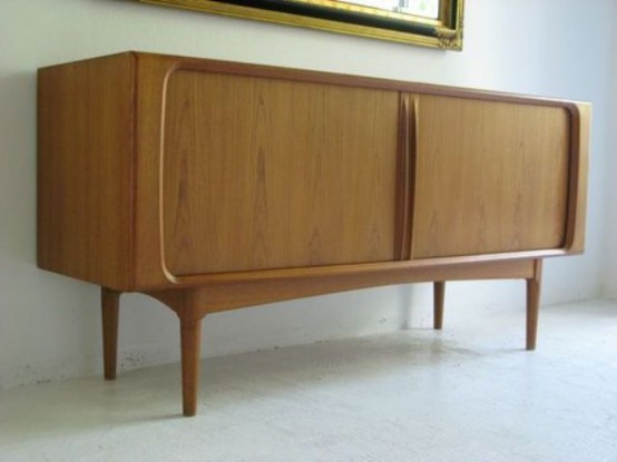 a light-stained mid-century modern sideboard with sliding doors and carved touches on tall legs is a cool idea for a modern space