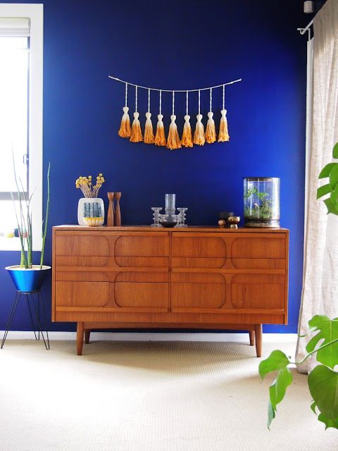 a catchy rich-stained sideboard with carved wooden doors on tall legs is a stylish and catchy idea for a mid-century modern space