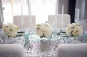 a silver and turquoise winter tablescape with white blooms, an ombre sequin tablecloth, mint glasses