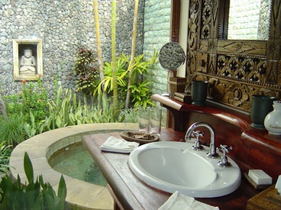 an Asian outdoor bathroom oasis with a large tub-pool, a sink, an inlay mirror and much greenery