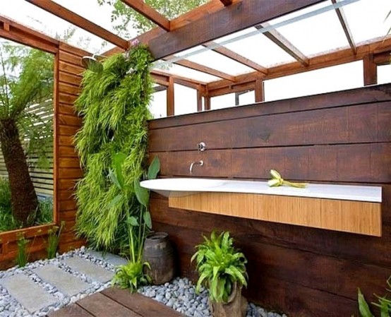 a contemporary outdoor shower space wiht a livign wall, pebbles and a floating sink